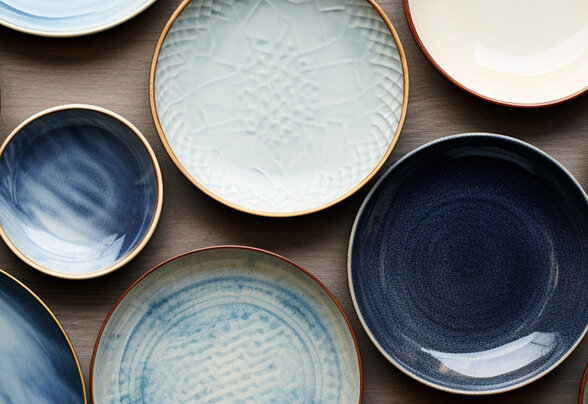 Various ceramic plates and porcelain dishes in blue, brown, and beige tones, neatly arranged on a white background. Generative AI. - Agrandir l'image, fenêtre modale